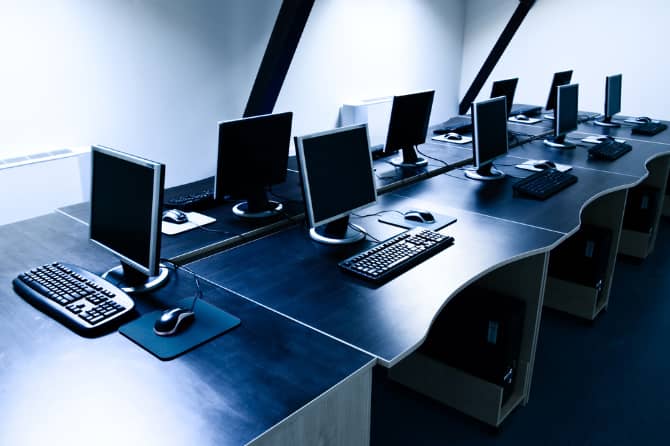 صورة لـ أسباب تجعل أجهزة Mac أقل عرضة للبرامج الضارة مقارنة بـ Windows | Computer-bank-with-multiple-Windows-computers-on-desks-min-DzTechs