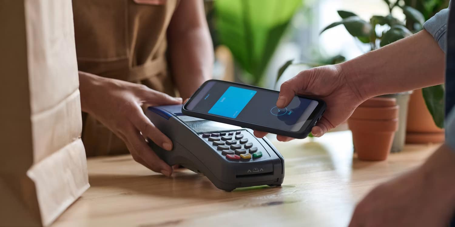 صورة لـ مُقارنة بين Google Pay و Samsung Pay: ما هي خدمة الدفع التي يجب أن تستخدمها؟ | a-guy-making-an-nfc-payment-using-his-smartphone-at-a-grocery-store