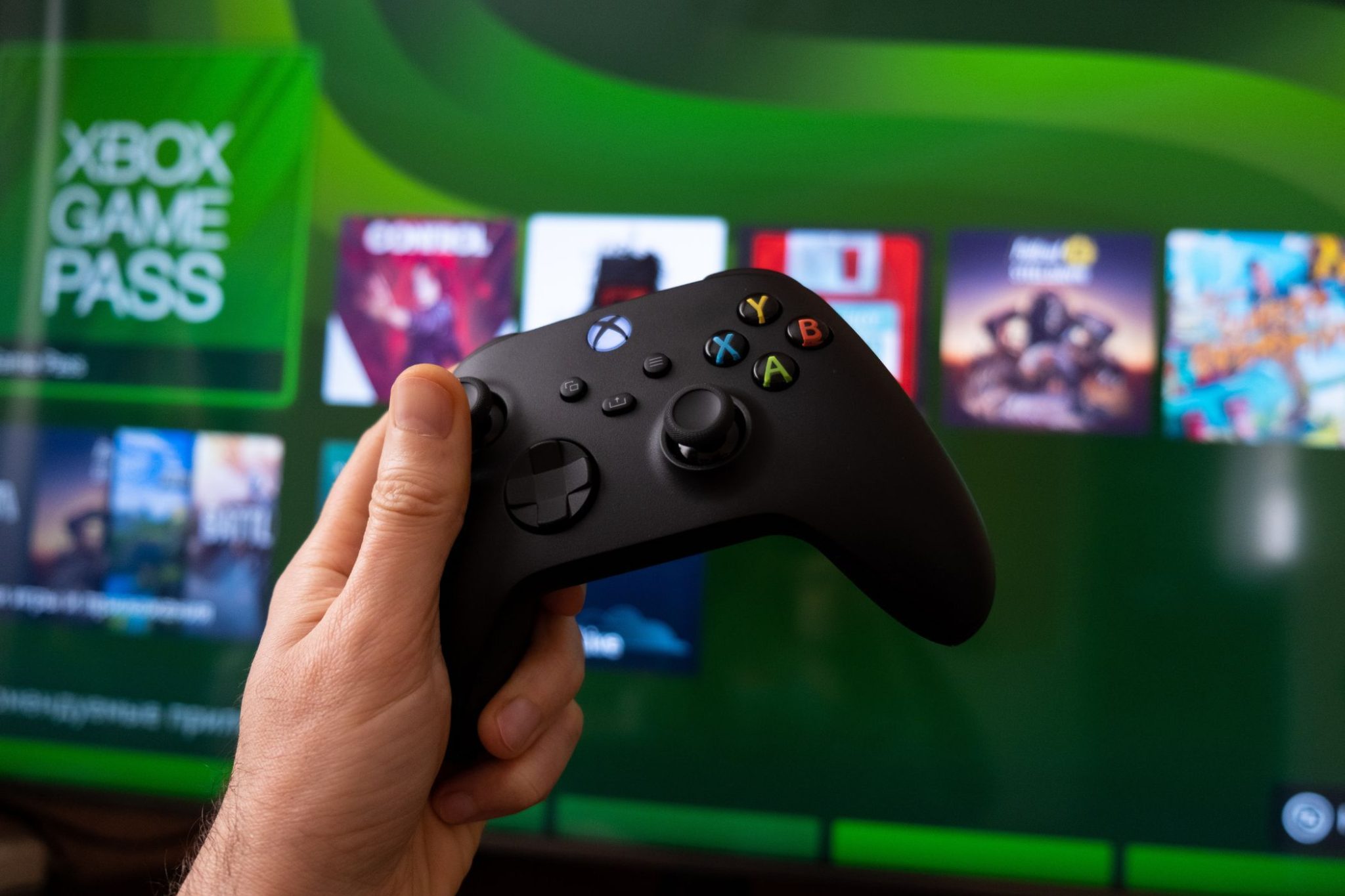 وحدة تحكم Xbox مع Xbox Game Pass على الشاشة في الخلفية