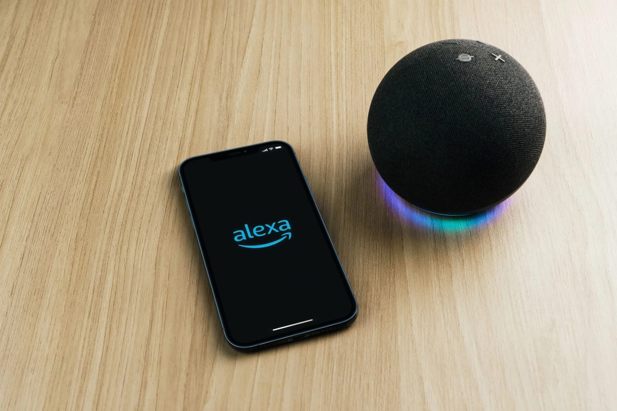تطبيق أليكسا على هاتف ذكي على طاولة بجانب مكبر صوت Echo