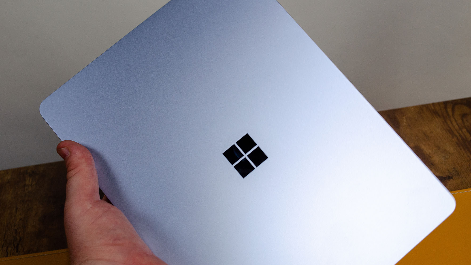 يد رجل تحمل جهاز Microsoft Surface Laptop بشاشة 13 بوصة