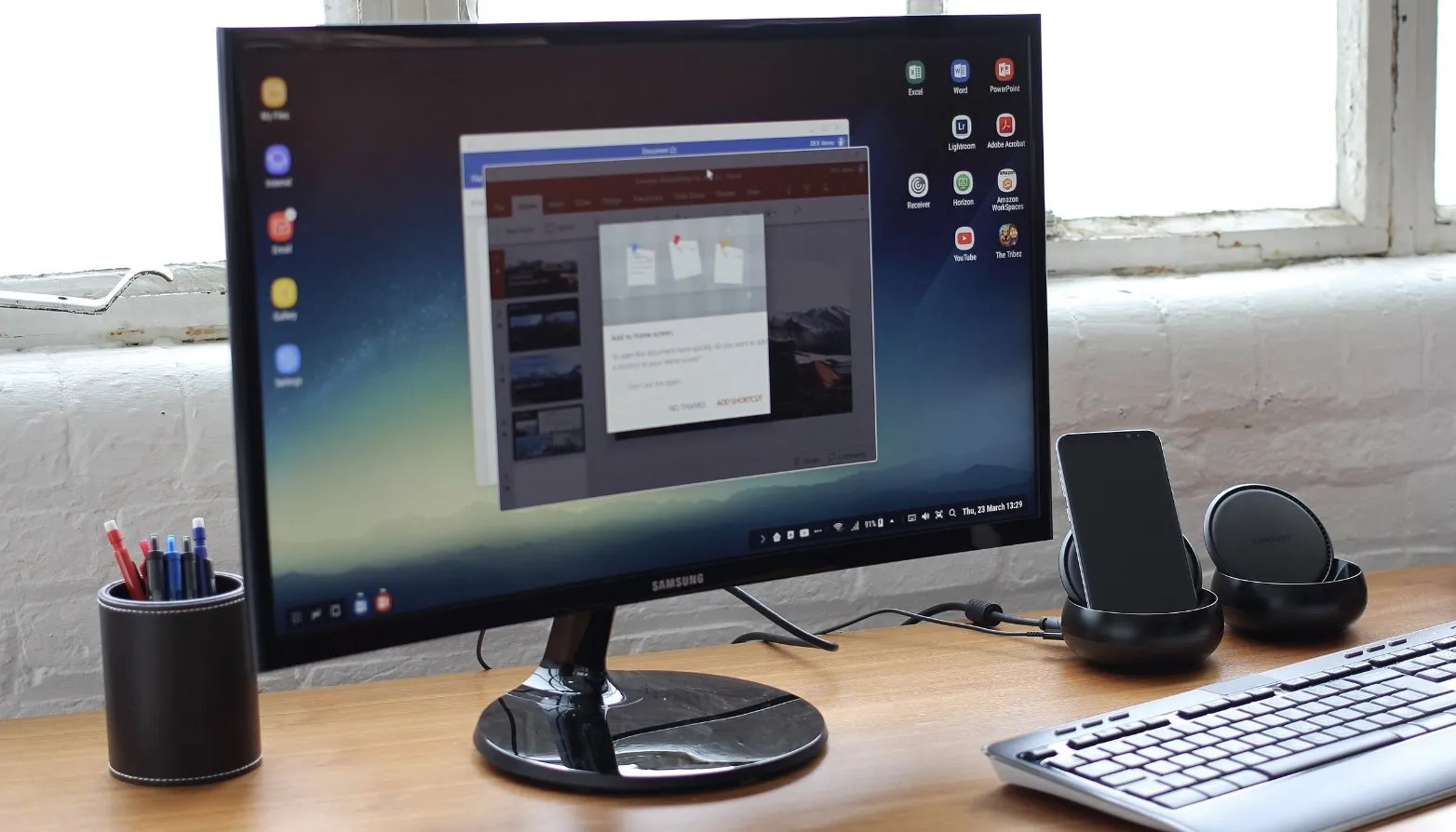 شاشة Samsung على مكتب مع لوحة مفاتيح ونظام صوت